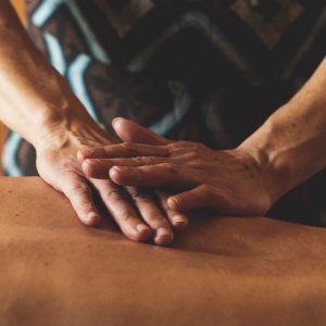 Gros plan sur les mains de Sarah en train de masser le milieu du dos d'un client.