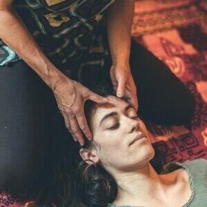 Plan rapproché sur Sarah qui masse la tête d'une jeune femme allongée sur un futon fermant les yeux.