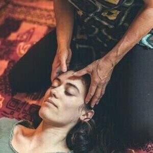 Plan rapproché sur le visage d'une jeune femme en train d'être massée délicatement par Sarah Arbaud, praticienne en massages bien-être.